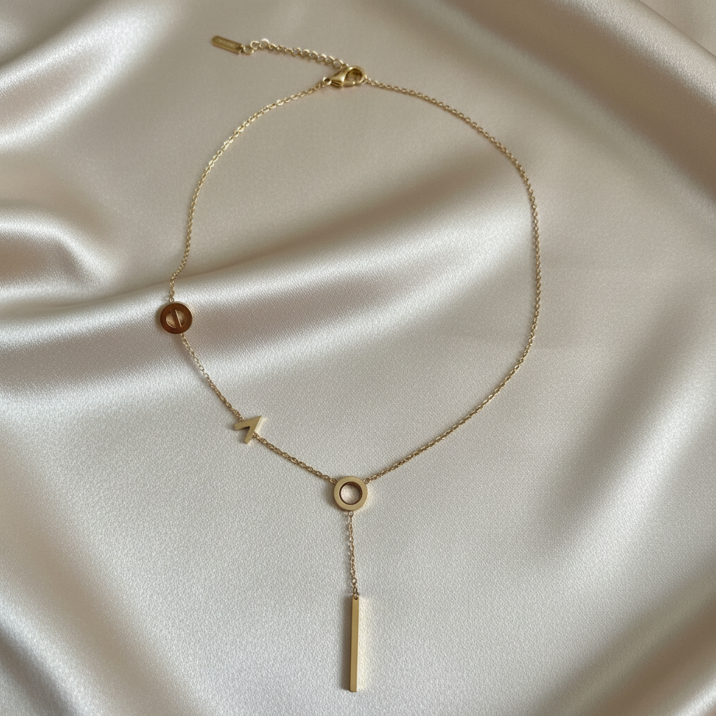 Gold geometric lariat Y-necklace on champagne satin background