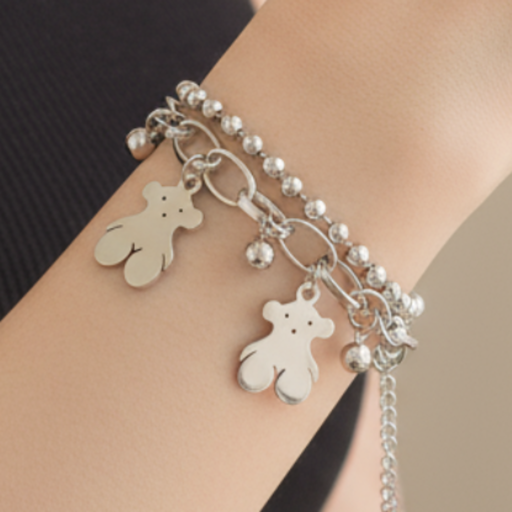Woman's wrist wearing silver layered bracelet with teddy bear charms